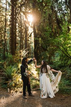 a bride and groom dancing in the woods at their elopement wedding ceremony with sun shining through the trees