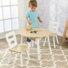 a young child playing with a wooden table and chair set in a playroom area