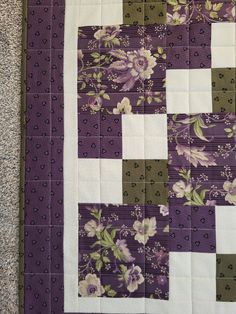 a purple and white quilt with flowers on it