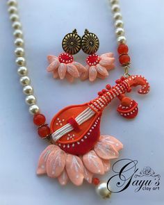 a necklace and earring set made out of glass beads, coral colored flowers with red accents