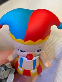 a close up of a small toy clown on a person's hand with an object in the background