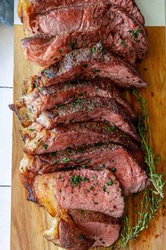 steak sliced up on a cutting board with herbs