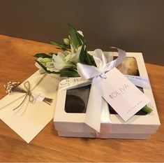 an open box with some flowers in it on top of a wooden table next to a card