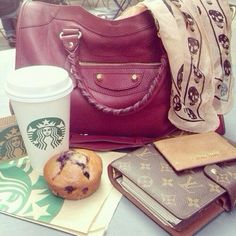 a purse, coffee cup and cookies are sitting on a table next to a starbucks bag