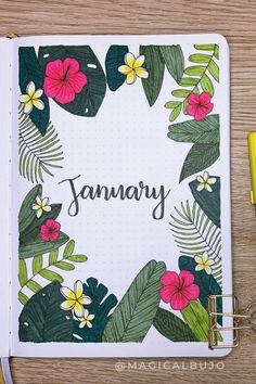 a notebook with the word january written on it next to a pen and some flowers