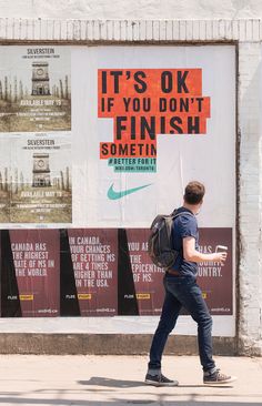 a man walking down the street in front of a poster