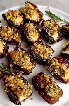 a white plate topped with stuffed dates covered in cheese and herbs on top of it