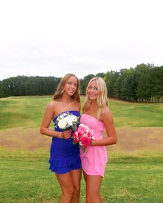 two beautiful young women standing next to each other in front of a golf course holding flowers