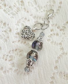 a close up of a keychain on a lace surface with a heart charm