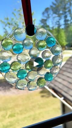 a glass ornament hanging on a window sill in front of a house