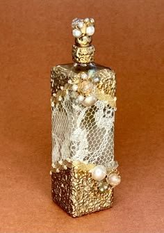 a decorative bottle with pearls and lace on it