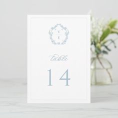 a white table number card with a floral arrangement in the background