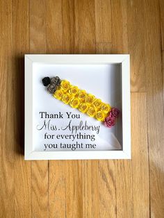 a white frame with yellow and red flowers in it on a wooden floor that says, thank you miss appleberry for everything you taught