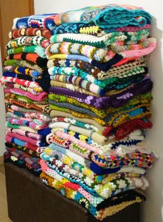 a large stack of colorful scarves sitting on top of a wooden table next to a doorway