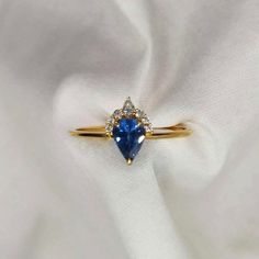 a blue sapphire and diamond ring sitting on top of a white cloth