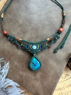 a necklace made with beads and stones on top of a piece of cloth next to feathers