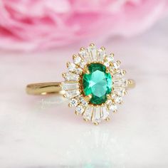 Beautiful Vintage Inspired Emerald Ring ►Base Metal: Sterling Silver (925) ►Plating: 14K Yellow Gold ►Accented With Simulated Diamonds (CZ) ►Average band width: 1.7 mm. ►Style: Art-Deco Center Stone: Emerald Gemstone Creation: Simulated Stone Shape: Oval Gem size: 7.0 x 5.0 mm Carat Weight: 0.76 ct. (Approx.) ✓ 100% Nickel-Free ✓ Hypoallergenic ✓ Comfort Fit ✓ Free Ring Box ✓ Free USA Shipping ►Please be aware that plated jewelry can wear off over time, if this is a concern we would suggest goin Timeless Emerald Anniversary Ring, Timeless Emerald Wedding Anniversary Ring, Timeless Cubic Zirconia Emerald Ring For Anniversary, Timeless Emerald Wedding Ring For May Birthstone, Heirloom May Birthstone Cluster Ring For Promise, Timeless Cubic Zirconia Emerald Wedding Ring, Timeless 14k Gold Emerald Wedding Ring, Classic Yellow Gold Emerald Ring With Halo, Heirloom Gold Emerald Ring With Halo Detail