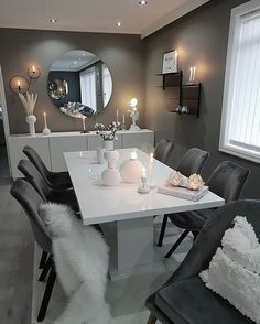 a dining room table with chairs and candles on it in front of a large mirror