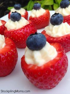 strawberries with whipped cream and blueberries on top sitting on a white platter