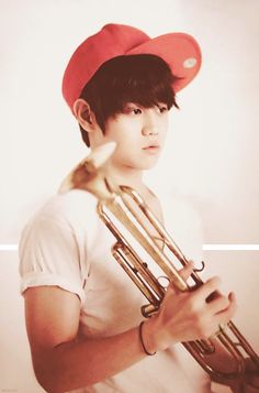 a young man wearing a red baseball cap and holding an instrument in his right hand