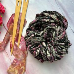 two skewers of yarn next to a pair of scissors on a marble surface