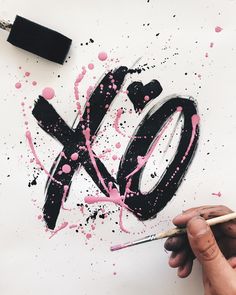 someone is painting the letters xo with black and pink paint on white paper,