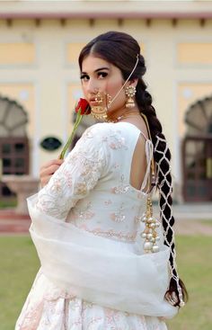 a woman with long hair wearing a white dress and holding a rose in her hand