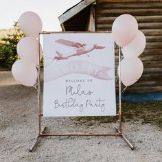 a welcome sign with balloons in front of a barn