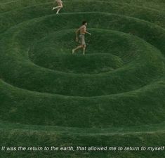 two people are running in the middle of a grassy area with an interesting spiral design