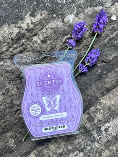 some lavender flowers are sitting on the ground next to a soap bar that says scenty