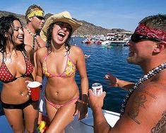 three women in bikinis are on a boat and one man is holding a drink