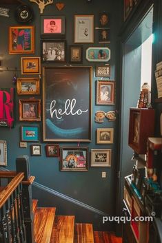 there are many framed pictures on the wall above the stairs in this room with wood flooring