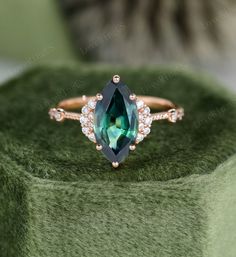 an emerald colored ring with white and pink diamonds sits on top of a green velvet