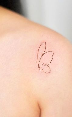 a small butterfly tattoo on the back of a woman's shoulder