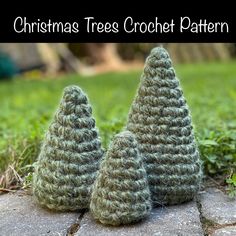 three crocheted christmas trees sitting on top of a stone slab in the grass