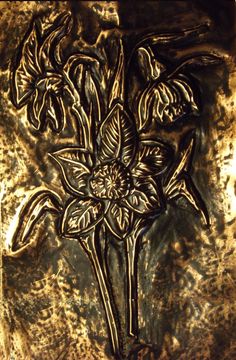 an intricately designed metal plate with flowers on it's side, in gold and black