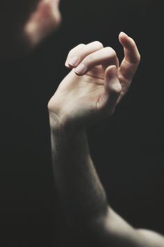 black and white photograph of two hands reaching for each other with their fingers extended up