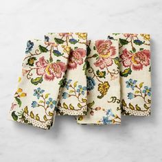 three napkins with floral designs on them sitting on a white counter top next to each other