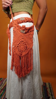 the woman is wearing an orange crocheted bag with fringes on it's sides