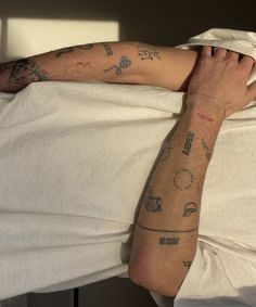 a man laying in bed with tattoos on his arm