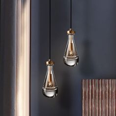 two silver and gold pendant lights hanging from the ceiling in a room with blue walls