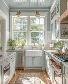 a kitchen filled with lots of white counter top space and wooden flooring next to a window