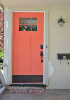 an orange front door on a white house