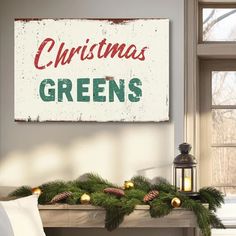 a christmas sign hanging on the side of a fireplace with pine cones and greenery