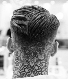 the back of a man's head with tattoos on his face and neck, in black and white