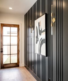 a hallway with black and white striped walls, wood flooring and an art piece hanging on the wall