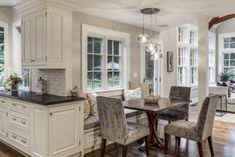 a kitchen with white cabinets and black counter tops next to a dining room table surrounded by chairs