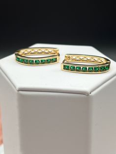 Emerald gold hoop earrings feature a circular design crafted in gold, adorned with multiple small, vivid green emeralds set along the outer edge. The emeralds sparkle elegantly, contrasting beautifully with the warm hue of the gold, creating a luxurious and sophisticated piece of jewelry. Elegant Green Huggie Jewelry, Green Round Gold-plated Earrings, Green Gold Plated Round Earrings, Green Gold-plated Round Earrings, Elegant Green Hoop Earrings For Formal Occasions, Green Emerald Hoop Earrings, Elegant Green Hoop Earrings, Elegant Emerald Huggie Earrings For May Birthstone, Elegant Gold Plated Green Hoop Earrings