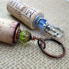 two wine corks with green glass bead on them are sitting on a table