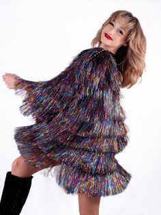 a woman in a multicolored dress and black boots posing for the camera with her legs spread out